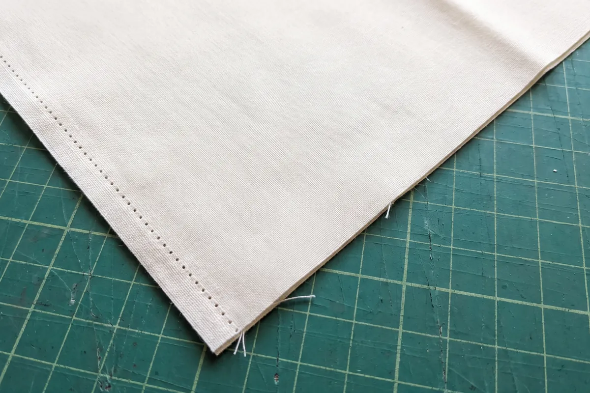 Corner of cotton fabric showing a firm woven selvage meeting a slightly frayed cut edge