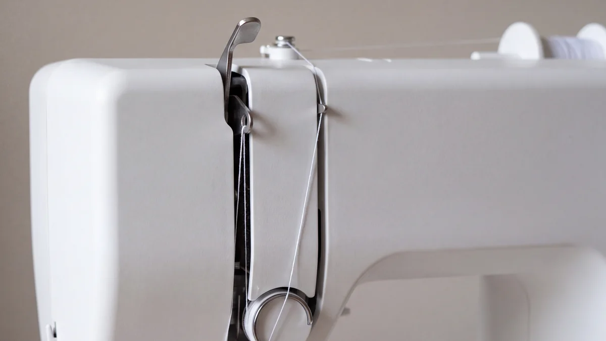 Thread passing through the eye of a raised take-up lever on a home sewing machine